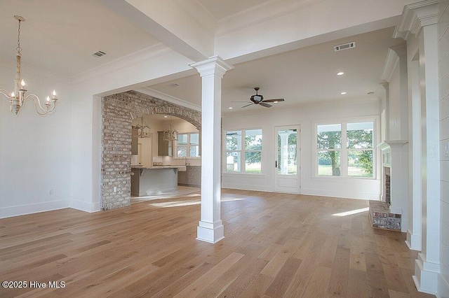 unfurnished living room with visible vents, light wood-style flooring, crown molding, decorative columns, and a brick fireplace