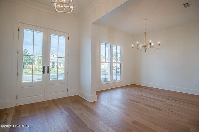 foyer entrance featuring a chandelier, visible vents, light wood-type flooring, and crown molding