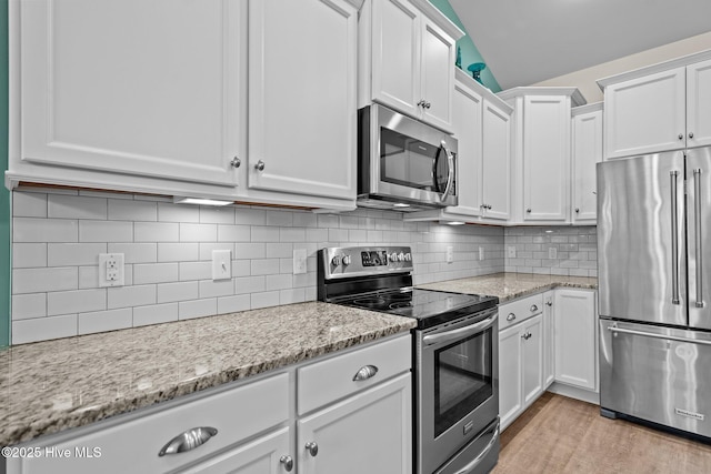 kitchen featuring white cabinetry, light wood-type flooring, tasteful backsplash, and stainless steel appliances