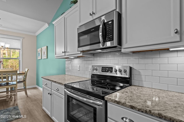 kitchen featuring tasteful backsplash, crown molding, light stone counters, appliances with stainless steel finishes, and light wood-style floors