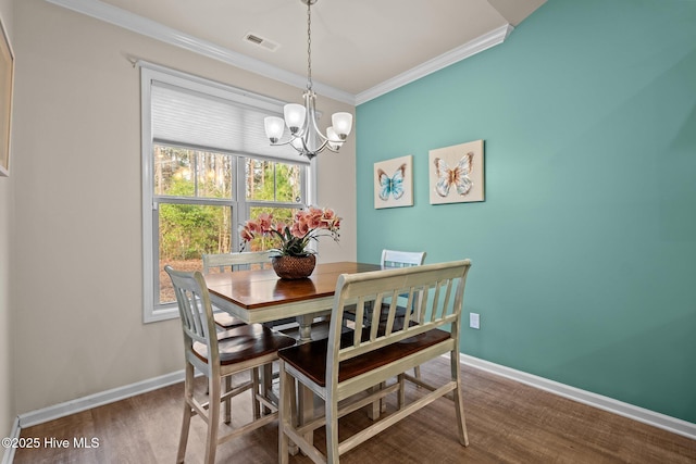 dining space featuring visible vents, ornamental molding, wood finished floors, baseboards, and a chandelier