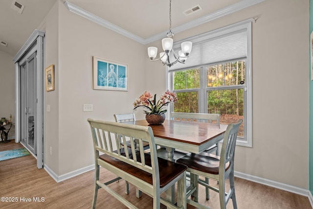 dining space featuring visible vents, a notable chandelier, light wood-style flooring, crown molding, and baseboards