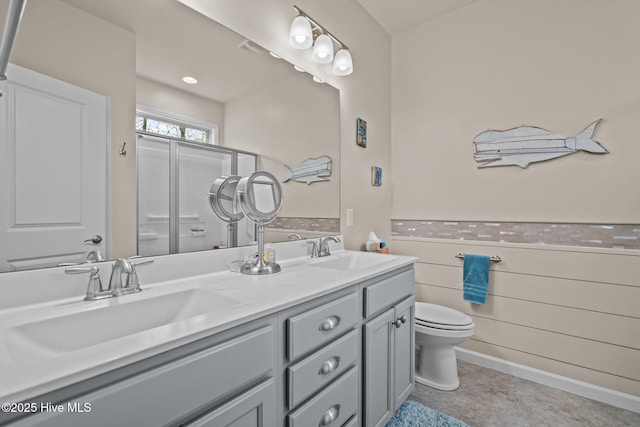 bathroom featuring double vanity, an enclosed shower, toilet, and a sink