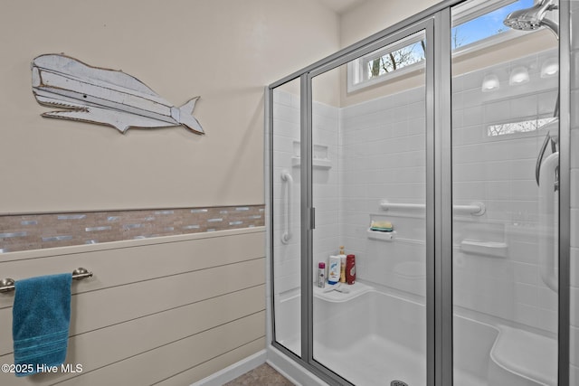 bathroom with a wainscoted wall and a stall shower