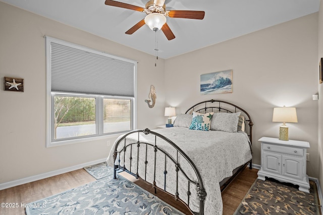 bedroom featuring ceiling fan, baseboards, and wood finished floors