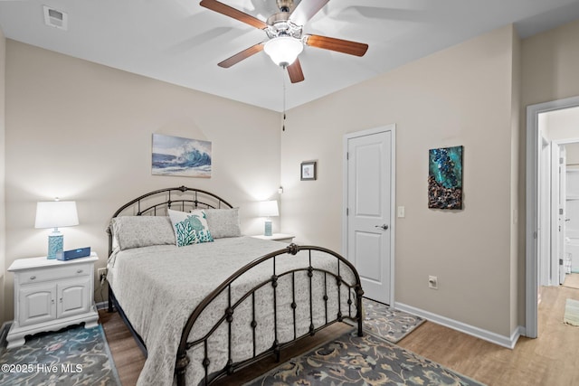 bedroom featuring a ceiling fan, wood finished floors, visible vents, and baseboards