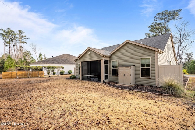 back of house featuring fence, roof with shingles, and a sunroom