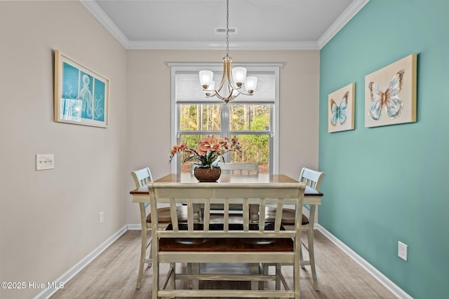 dining space with visible vents, wood finished floors, an inviting chandelier, and ornamental molding