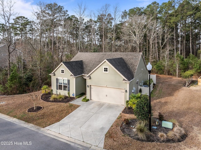 traditional home with an attached garage, driveway, and a shingled roof