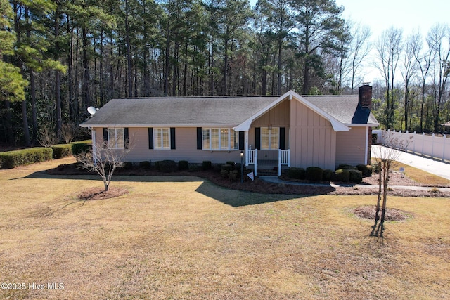 single story home with a chimney, a porch, a front lawn, and fence