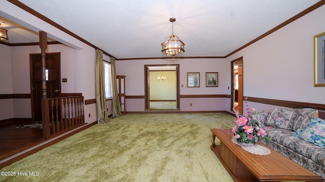 carpeted living room with a notable chandelier, baseboards, and ornamental molding