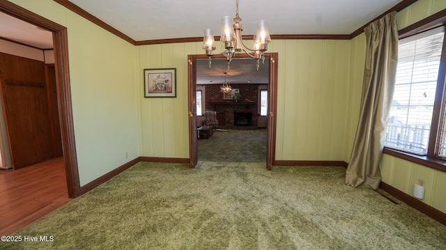 unfurnished dining area with baseboards, crown molding, an inviting chandelier, and carpet floors