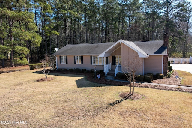 view of front facade with board and batten siding, a chimney, and a front lawn