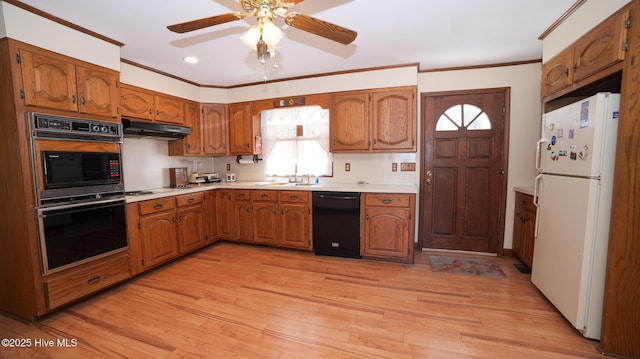 kitchen with under cabinet range hood, brown cabinets, light wood-style floors, and black appliances