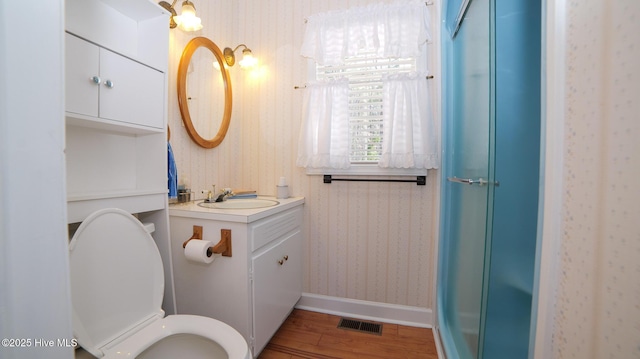 full bathroom with wallpapered walls, vanity, wood finished floors, and visible vents