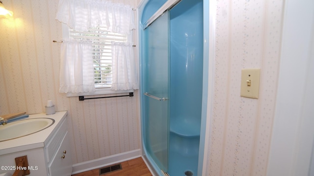 bathroom with visible vents, a stall shower, wood finished floors, wallpapered walls, and vanity