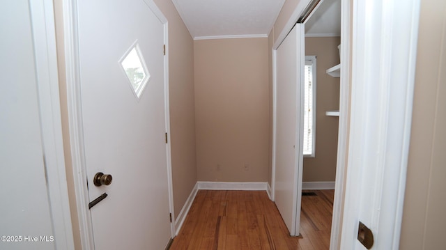 hallway featuring light wood-type flooring, baseboards, and crown molding