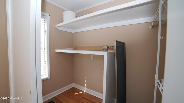 clothes washing area with baseboards, wood finished floors, and ornamental molding