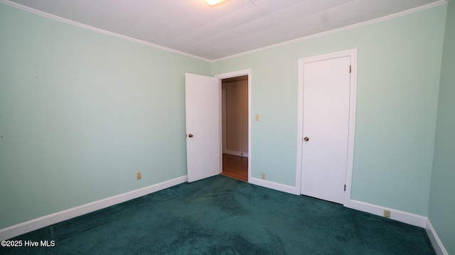 empty room with crown molding, baseboards, and dark colored carpet