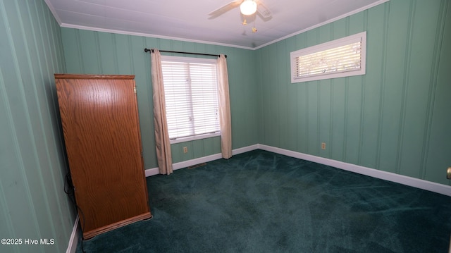 unfurnished room with ceiling fan, baseboards, dark colored carpet, and ornamental molding