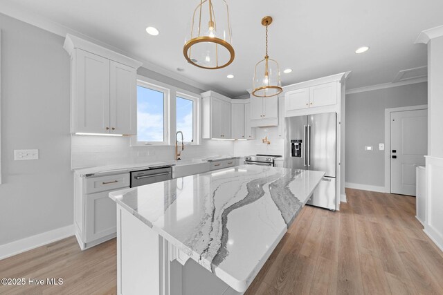 304 Alabama Ave Unit 2, Carolina Beach, NC 28428 - kitchen featuring crown molding, white cabinets, appliances with stainless steel finishes, a center island, and light wood-type flooring