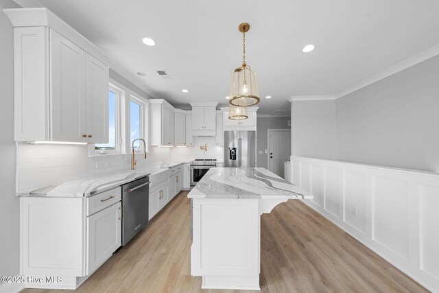 304 Alabama Ave Unit 2, Carolina Beach, NC 28428 - kitchen featuring a sink, a center island, ornamental molding, white cabinets, and appliances with stainless steel finishes