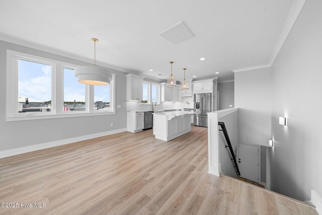 304 Alabama Ave Unit 2, Carolina Beach, NC 28428 - kitchen featuring a center island, crown molding, light countertops, white cabinets, and appliances with stainless steel finishes