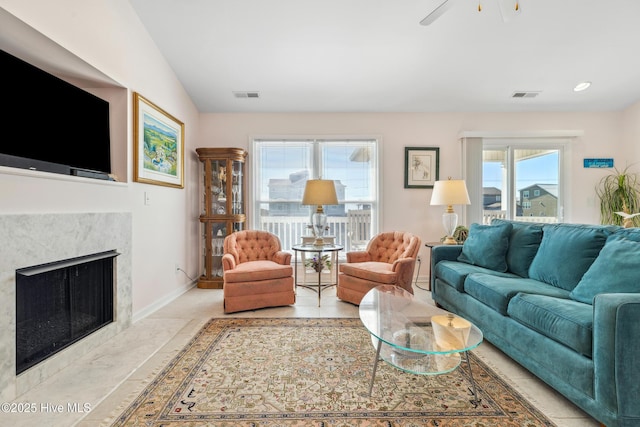 living room featuring vaulted ceiling, baseboards, visible vents, and a premium fireplace