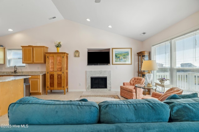 living area with lofted ceiling, baseboards, visible vents, and a high end fireplace