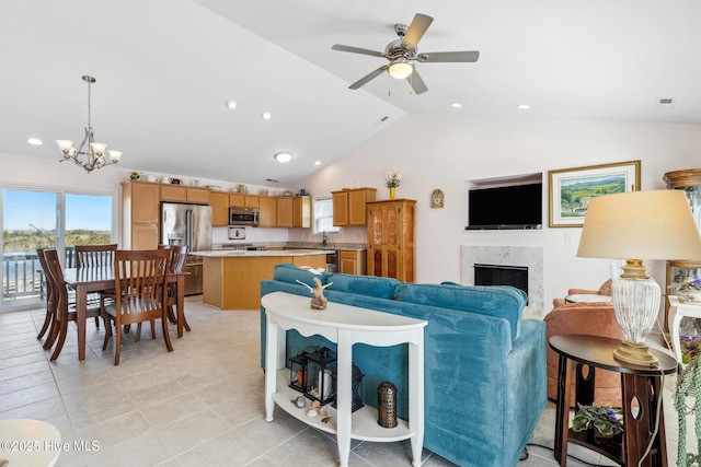 living area with light tile patterned floors, a premium fireplace, recessed lighting, vaulted ceiling, and ceiling fan with notable chandelier