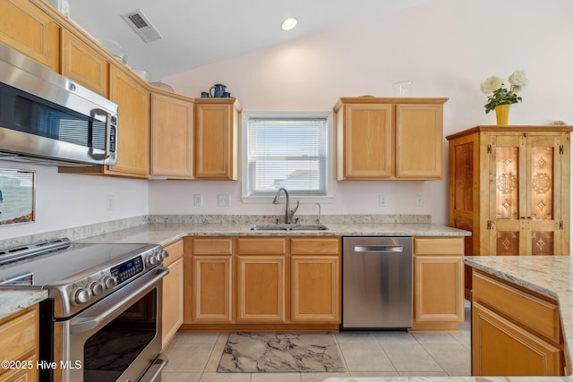 kitchen featuring visible vents, light stone countertops, lofted ceiling, stainless steel appliances, and a sink