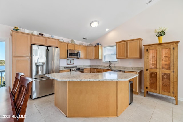 kitchen with a kitchen island, vaulted ceiling, light tile patterned floors, stainless steel appliances, and a sink