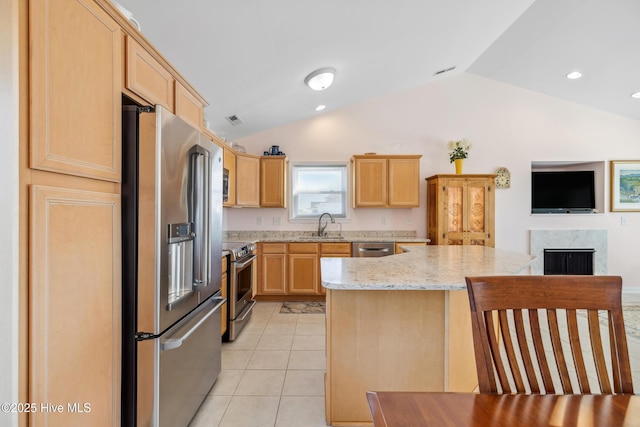 kitchen featuring light tile patterned floors, stainless steel appliances, a center island, and light brown cabinets