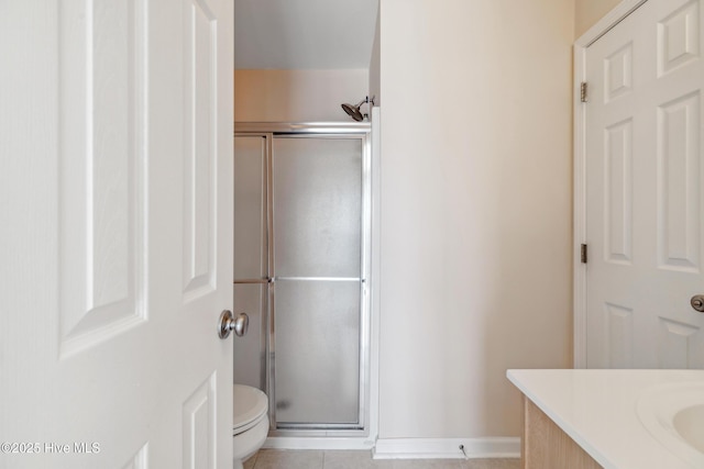 full bathroom featuring vanity, baseboards, a stall shower, tile patterned flooring, and toilet