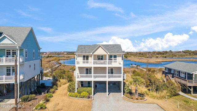 view of property featuring gravel driveway, a carport, and a water view