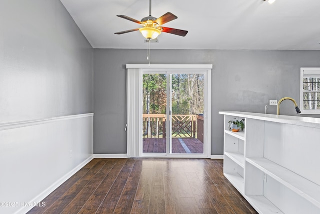 unfurnished dining area featuring ceiling fan, baseboards, and hardwood / wood-style floors