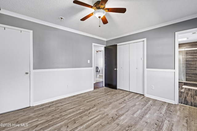 unfurnished bedroom featuring a textured ceiling, wood finished floors, ensuite bathroom, and ornamental molding