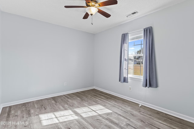 spare room featuring visible vents, baseboards, wood finished floors, and a ceiling fan