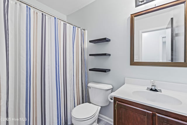 bathroom featuring toilet, vanity, and baseboards