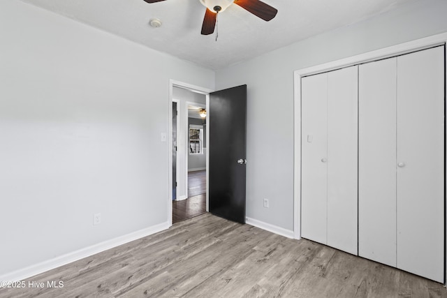 unfurnished bedroom featuring a ceiling fan, wood finished floors, baseboards, and a closet