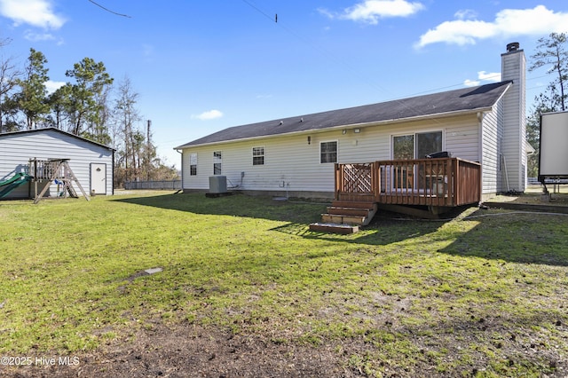 rear view of property featuring a wooden deck, a lawn, cooling unit, a chimney, and an outdoor structure