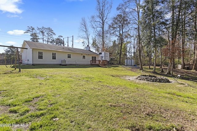 view of yard featuring a deck, an outbuilding, a storage unit, and an outdoor fire pit