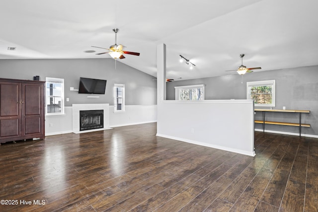 unfurnished living room with visible vents, dark wood-type flooring, a fireplace with flush hearth, vaulted ceiling, and a ceiling fan