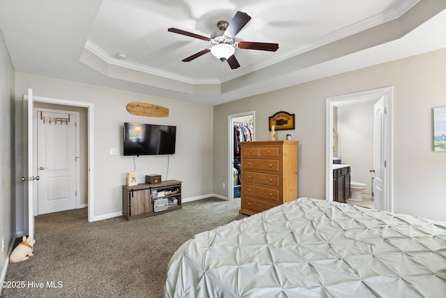 carpeted bedroom featuring a raised ceiling, ornamental molding, a closet, baseboards, and a spacious closet