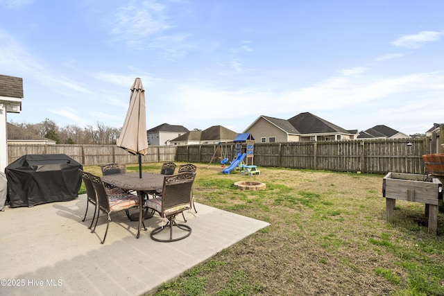 view of yard featuring a patio area, outdoor dining space, a playground, and a fenced backyard