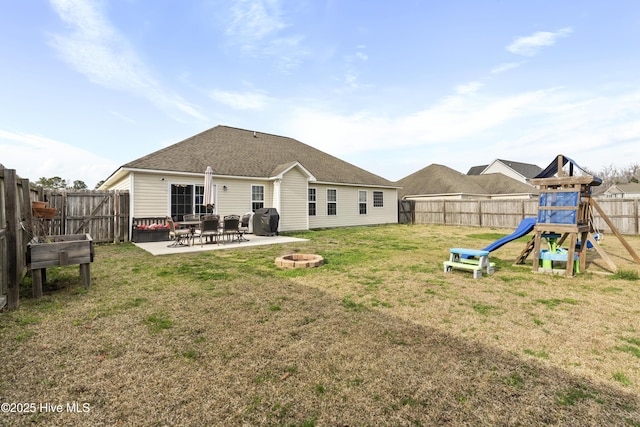 back of house with a lawn, a patio, a fenced backyard, a playground, and a fire pit