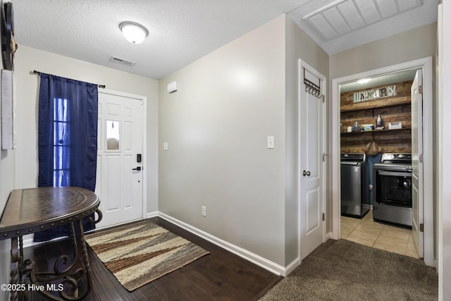 entrance foyer with baseboards, visible vents, independent washer and dryer, and a textured ceiling