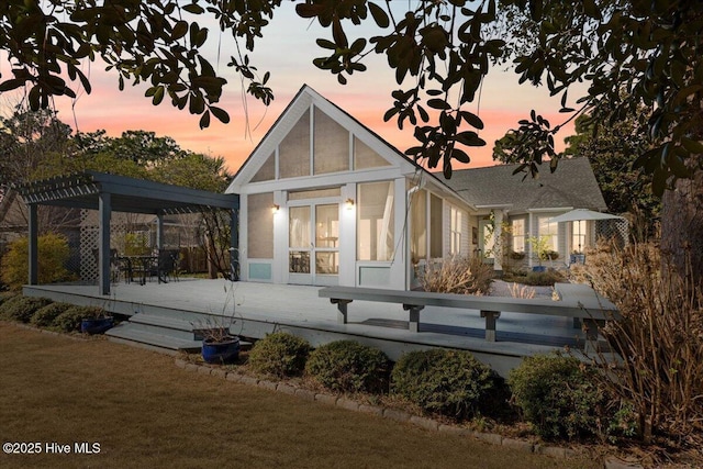 rear view of house featuring a lawn, a deck, and a pergola