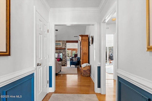 hall with wainscoting, crown molding, and light wood-style floors