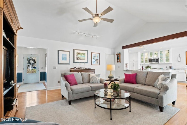 living room featuring a ceiling fan, baseboards, light wood finished floors, and high vaulted ceiling